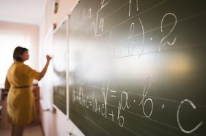 teacher-writing-chalkboard_23-2148665921