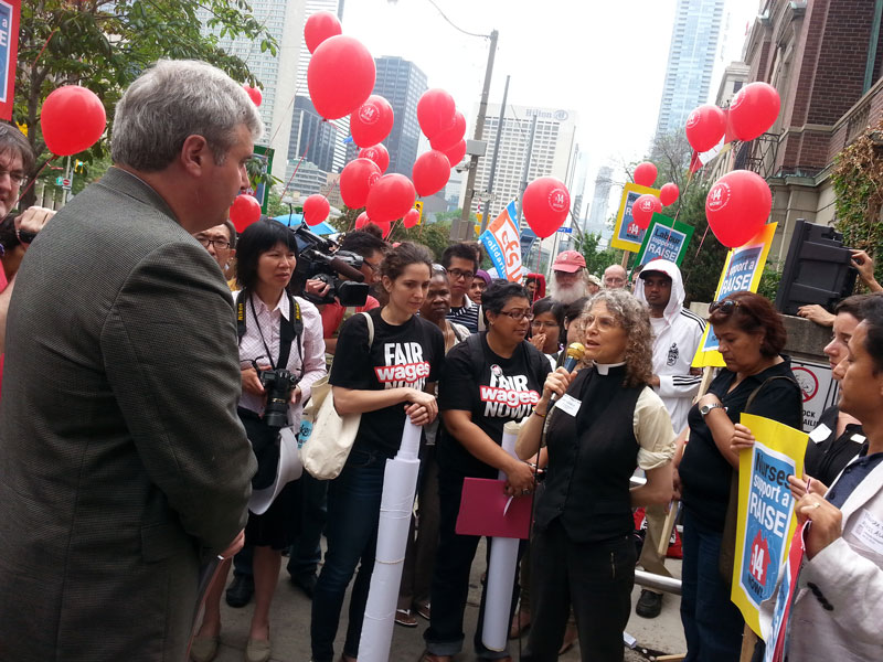 加拿大聖公會（Anglican Church of Canada）的代表Maggie Helwig向勞工廳新聞負責人Tom Zach(右)講述，現在最低工資的標準仍無法讓他們自食其力。