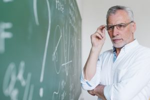 concentrated-aged-math-teacher-looking-chalkboard_23-2148201016