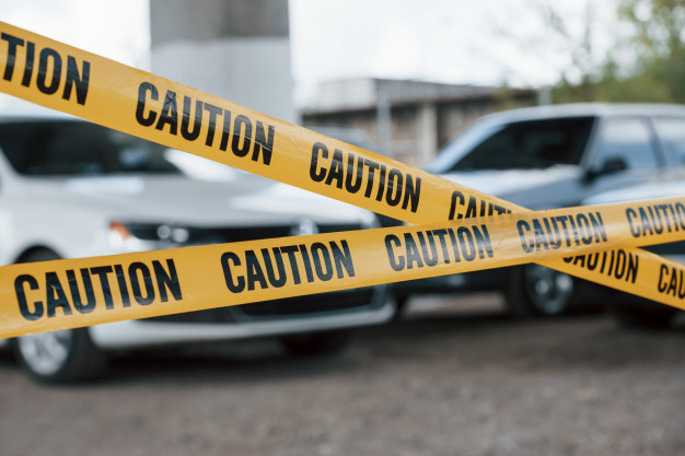 black-white-vehicles-yellow-caution-tape-near-car-parking-lot-daytime-crime-scene_146671-16659