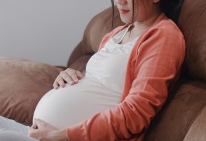 Young Asian Pregnant woman holding her belly talking with her ch